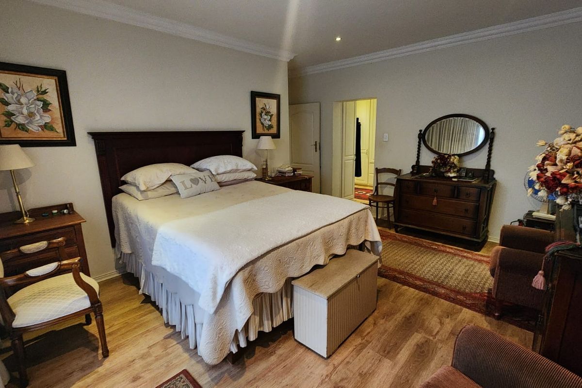 A well-maintained bedroom featuring laminate flooring, crown molding, and recessed lighting, providing a comfortable and classic living space.
