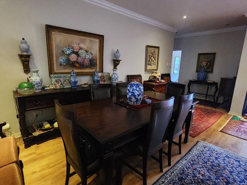 A formal dining room featuring laminate flooring, recessed downlighting, and decorative cornicing, providing a classic and well-maintained space for entertaining.