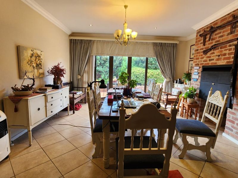 Dining room featuring tiled flooring, an exposed brick fireplace, and sliding glass doors providing natural light and access to the garden.