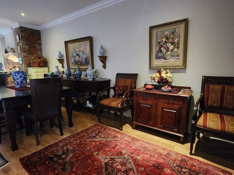 Open plan dining area featuring laminate flooring, crown molding, and a brick feature wall, seamlessly connected to the kitchen space.