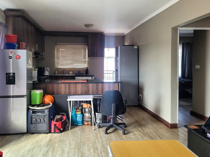 Open-plan kitchen area featuring wood-look laminate flooring, dark cabinetry, and a breakfast counter, providing a functional layout for modern apartment living.