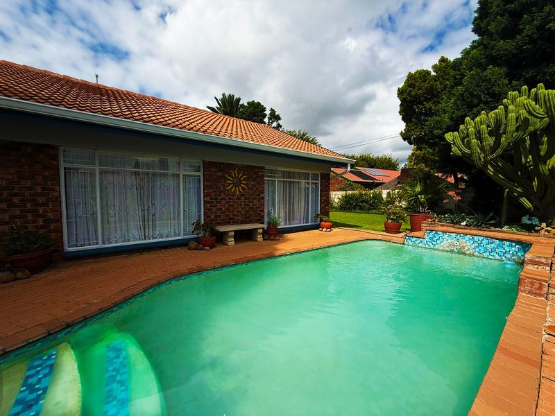 Outdoor pool area featuring a brick-clad home exterior, tiled patio surround, and a swimming pool with integrated steps.
