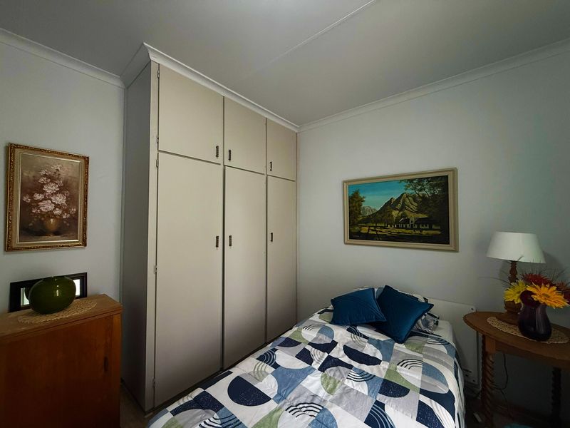 A functional bedroom featuring built-in cupboards and coved cornices, offering a clean and well-maintained space.