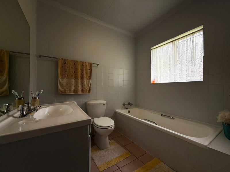 A functional bathroom featuring a built-in vanity, toilet, and bathtub with tiled finishes throughout.