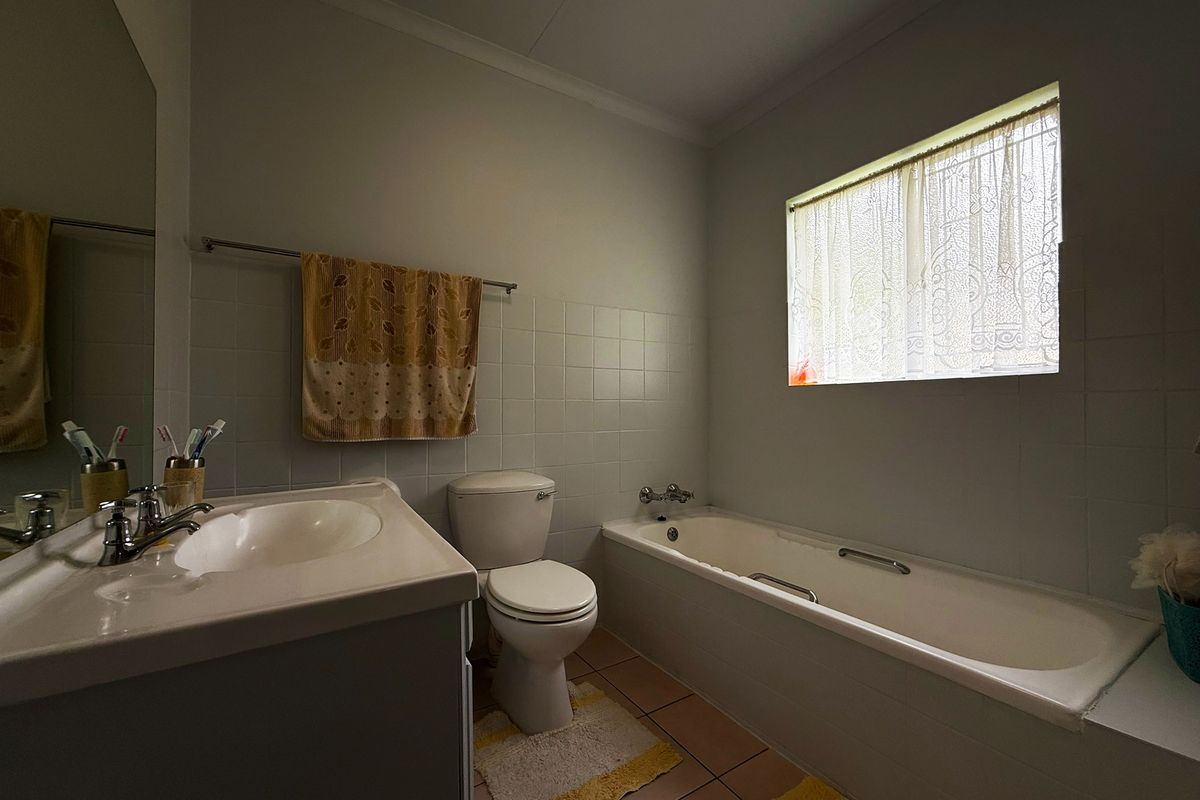 A functional bathroom featuring a built-in vanity, toilet, and bathtub with tiled finishes throughout.