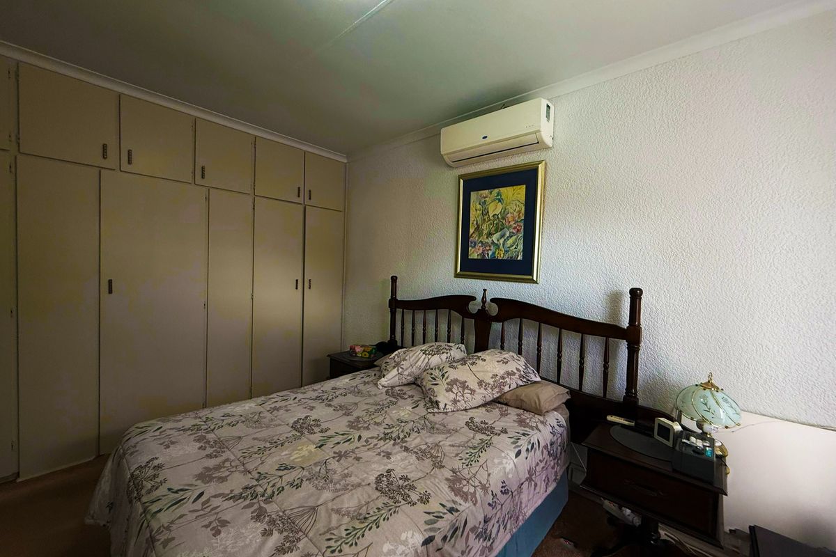 A bedroom featuring built-in cupboards and a wall-mounted split-system air conditioning unit.