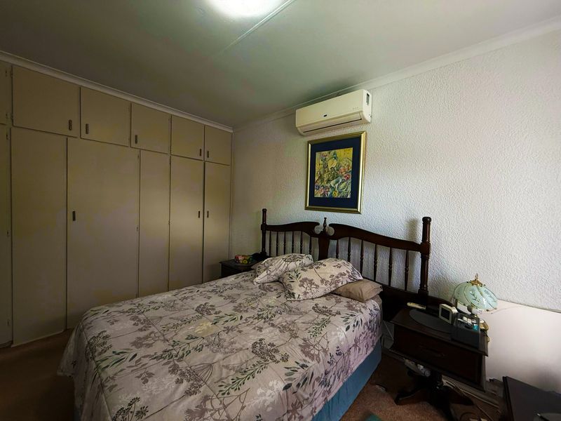 A bedroom featuring built-in cupboards and a wall-mounted split-system air conditioning unit.