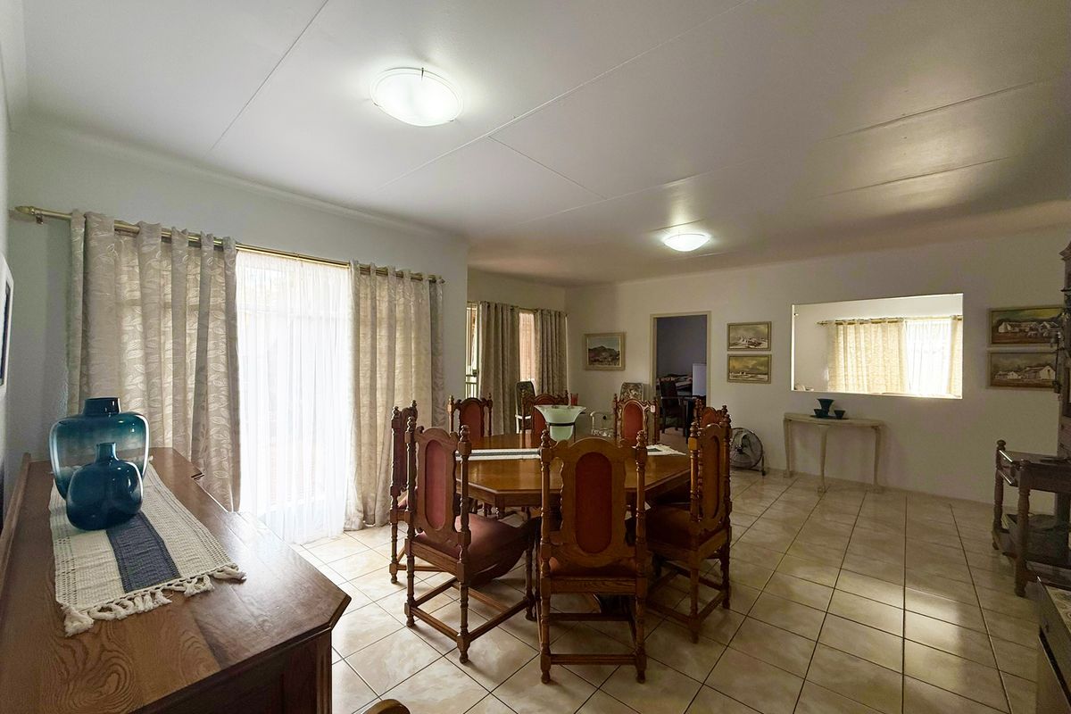 Spacious dining room featuring neutral tiled flooring, large sliding glass doors for natural light, and a convenient pass-through window to the adjacent area.