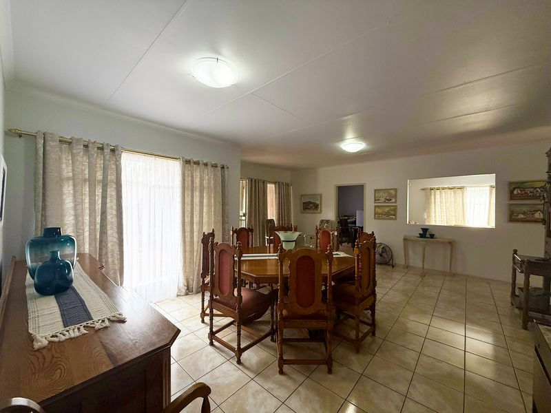 Spacious dining room featuring neutral tiled flooring, large sliding glass doors for natural light, and a convenient pass-through window to the adjacent area.