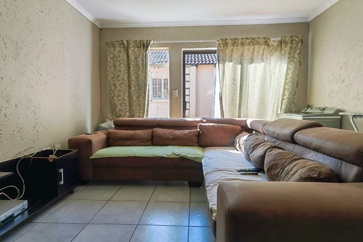A living room featuring tiled flooring and textured wall finishes, providing a functional space with direct access to an outdoor area.