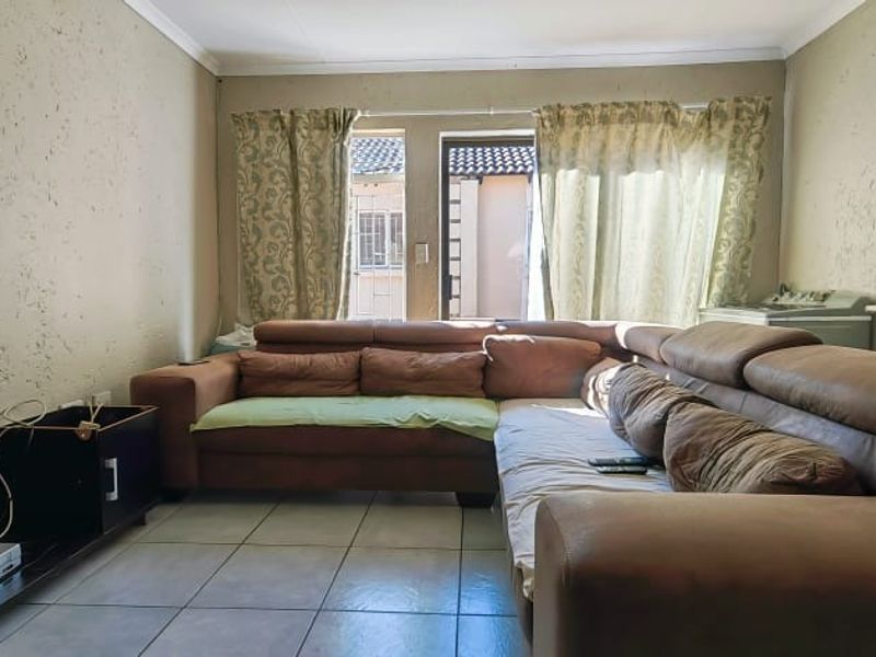 A living room featuring tiled flooring and textured wall finishes, providing a functional space with direct access to an outdoor area.