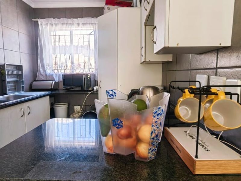 A functional kitchen featuring dark granite countertops, tiled splashbacks, and ample built-in cabinetry with a double basin sink.