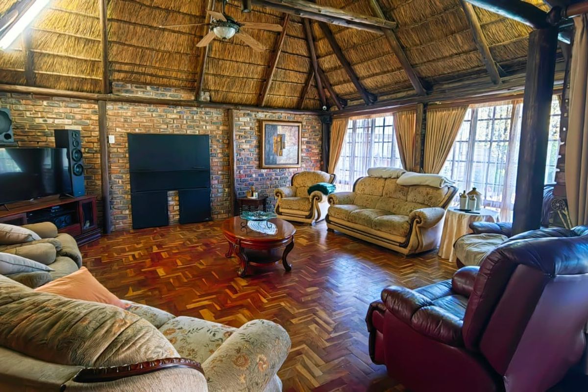 Spacious living room featuring a traditional thatched roof, exposed brick walls, and classic parquet flooring, creating a warm and rustic atmosphere.