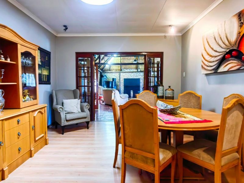 A dining room featuring laminate flooring and double french doors leading to an adjacent living area.