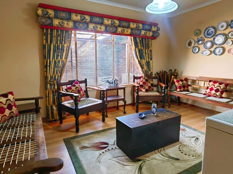 A cozy living room featuring laminate flooring, a built-in wall cabinet, and large windows with fitted blinds, offering a warm and traditional atmosphere.