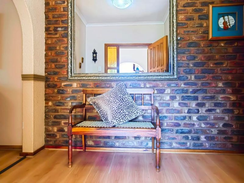 Welcoming entrance hall featuring a characterful exposed brick feature wall, arched transition, and warm laminate flooring.