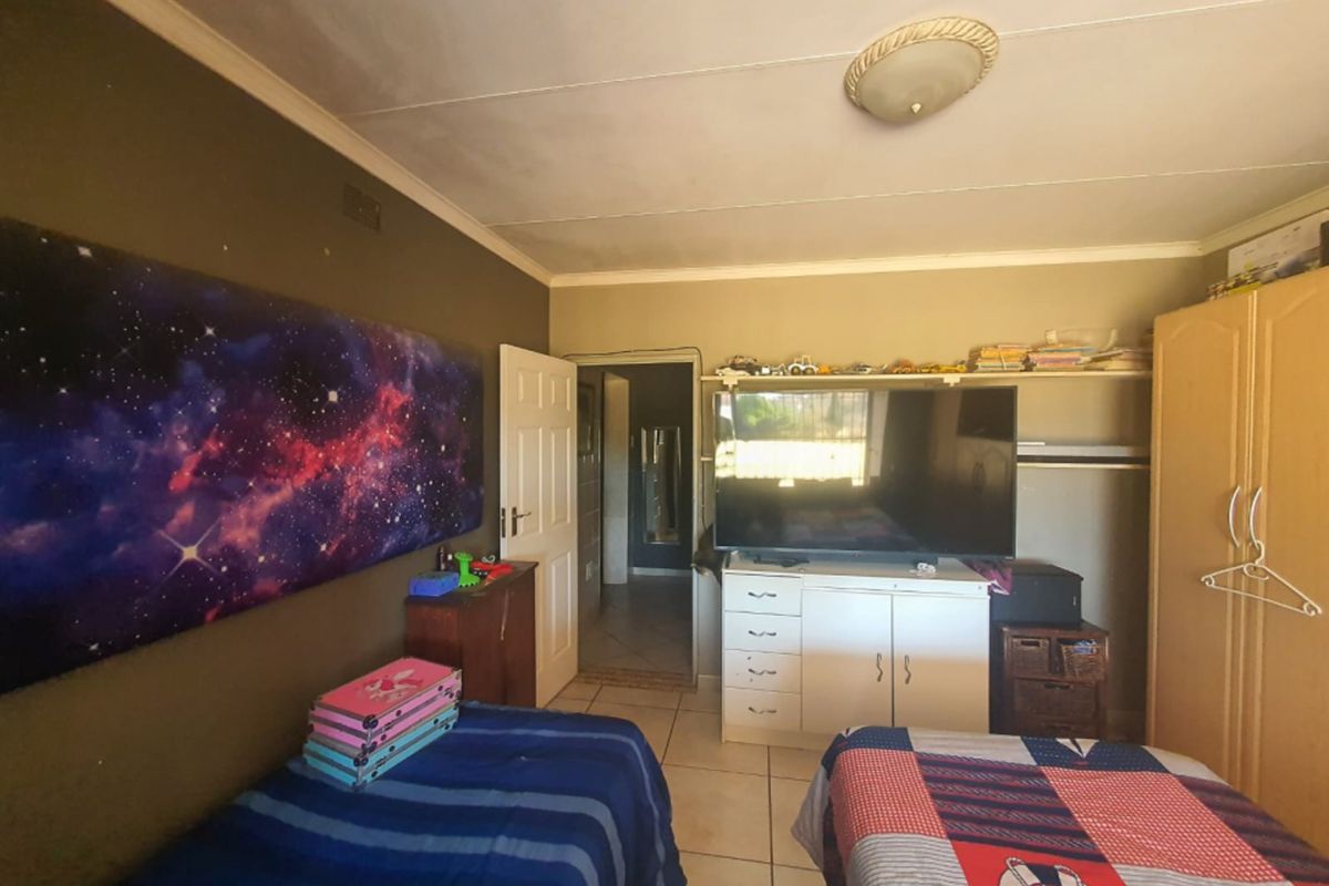 A bedroom featuring tiled flooring and built-in shelving, showing signs of wear including visible ceiling damage.