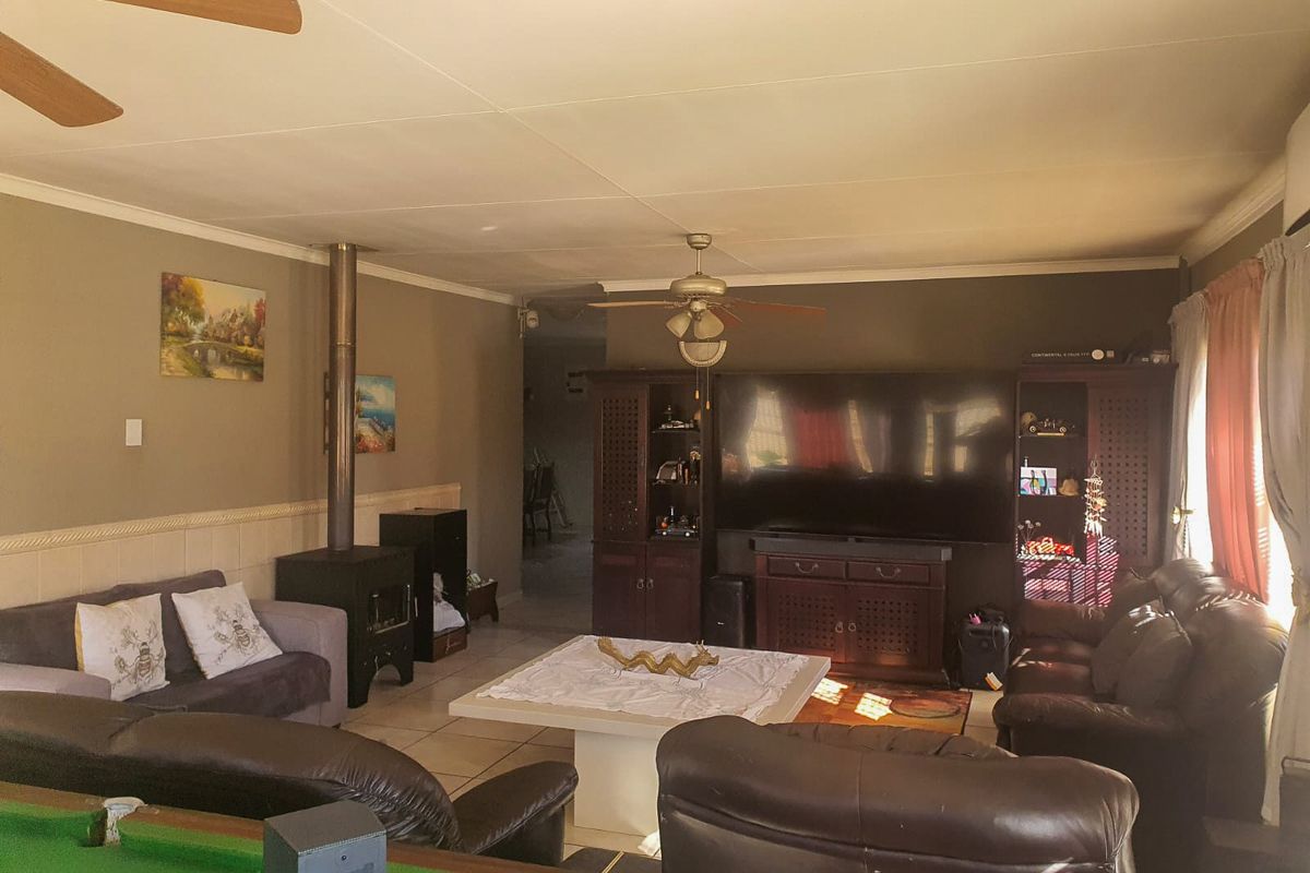Spacious living room featuring a wood-burning fireplace, tiled flooring, and a ceiling fan, offering a comfortable and functional family living space.