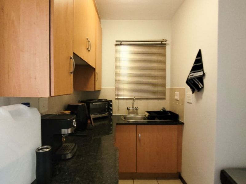 Compact kitchen featuring laminate cabinetry, dark granite countertops, stainless steel sink, and tiled flooring with a window providing natural light.