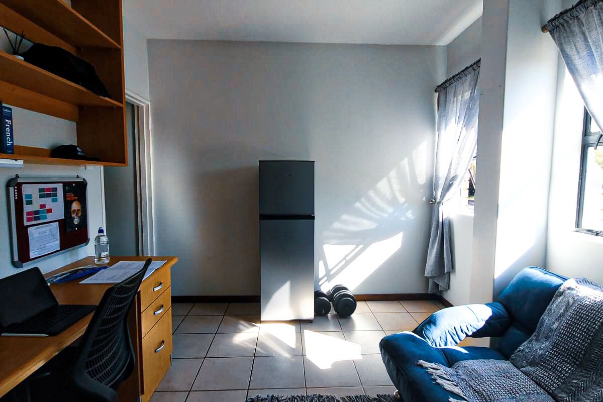 A functional bedroom featuring tiled flooring, built-in shelving, and natural light from the window.