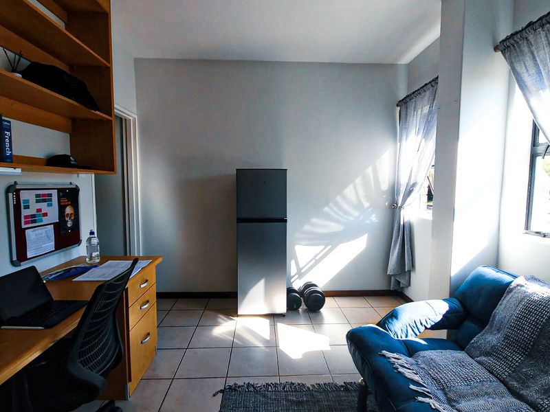 A functional bedroom featuring tiled flooring, built-in shelving, and natural light from the window.