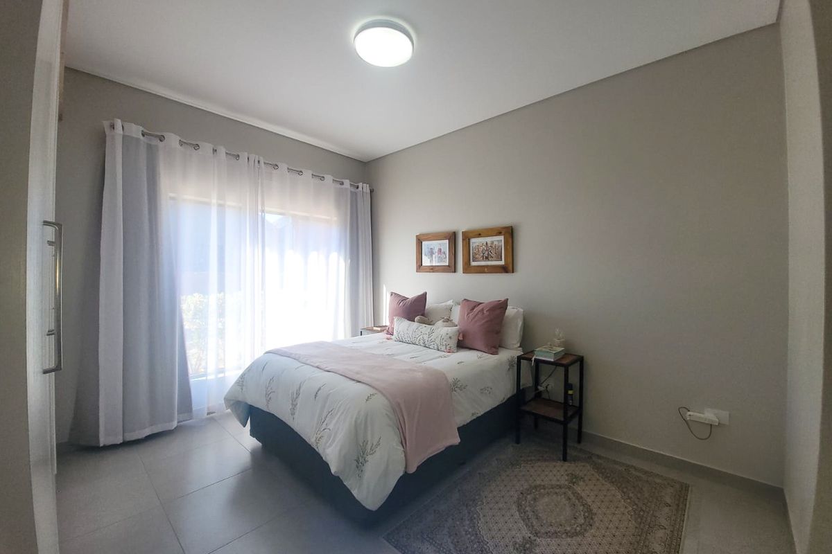 A well-maintained bedroom featuring neutral wall tones, tiled flooring, and a sliding glass door providing natural light.