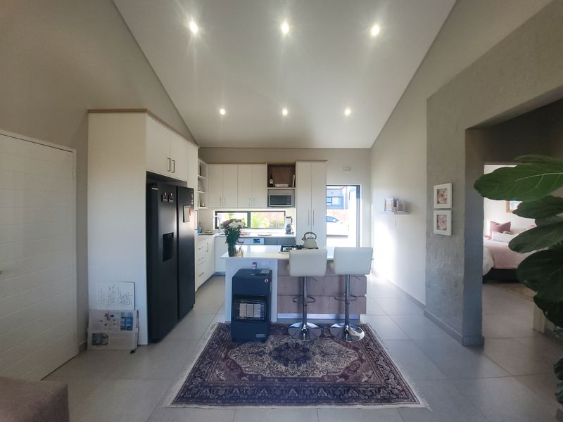 Modern open-plan kitchen featuring sleek cabinetry, a central island, and vaulted ceilings with recessed lighting, creating a bright and spacious living environment.