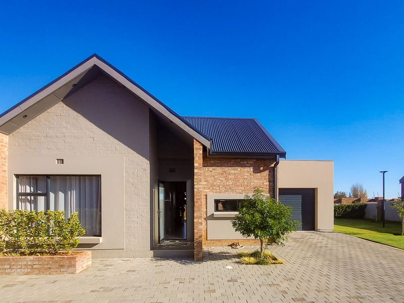 Modern townhouse exterior featuring a combination of brick and rendered finishes, a paved driveway, integrated garage, and a well-maintained front garden.
