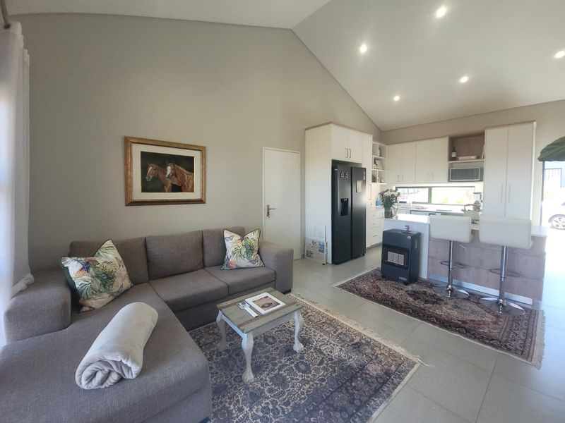 Modern open-plan living area featuring a vaulted ceiling, tiled floors, and a contemporary kitchen with a central island and ample built-in cabinetry.
