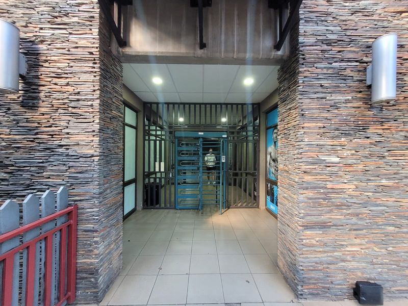 Secure building entrance featuring stacked stone facade, tiled flooring, and a metal turnstile access control system.