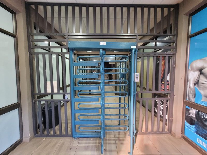 Secure building entrance featuring a metal turnstile and access control system, providing controlled entry to the facility.