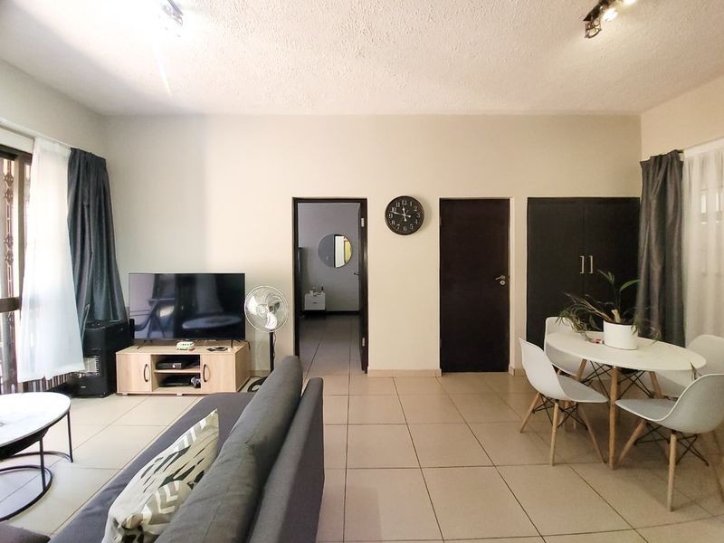 Open plan living and dining area featuring neutral tiled flooring and a built-in storage cupboard.