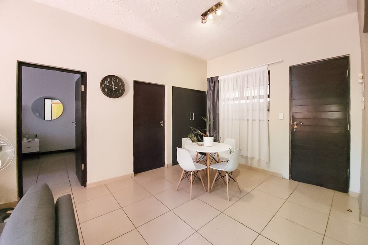 A living area featuring neutral tiled flooring, built-in storage cabinetry, and multiple internal doors leading to adjacent rooms.