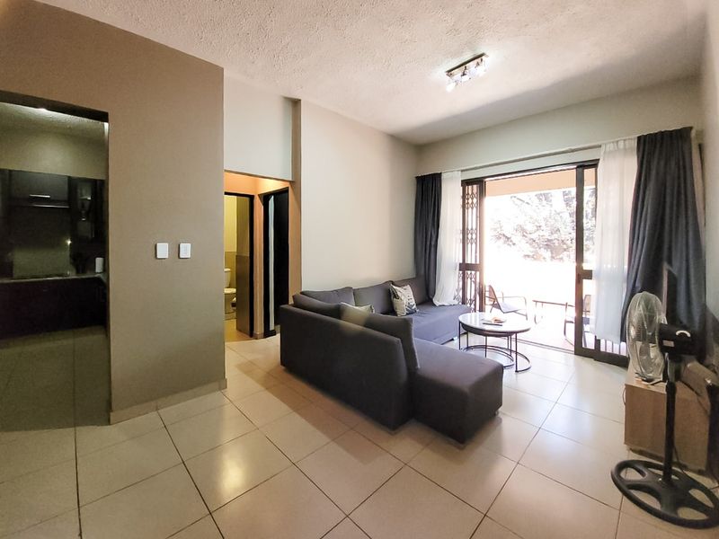 Open plan living area featuring tiled flooring and a sliding glass door leading to an outdoor patio space.