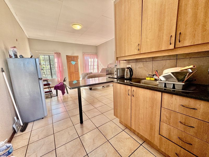 Open-plan studio apartment featuring a functional kitchen with laminate cabinetry, granite countertops, and tiled flooring throughout the living and sleeping area.