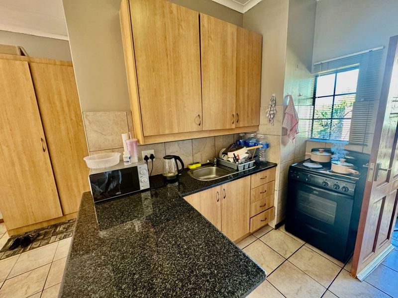 Compact kitchen featuring granite countertops, light wood-finish cabinetry, tiled backsplash, and a freestanding stove, providing a functional workspace.