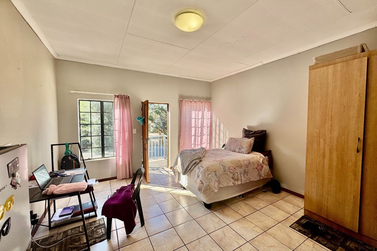 A bedroom featuring tiled flooring, a built-in wardrobe, and direct access to a balcony through a glass door.