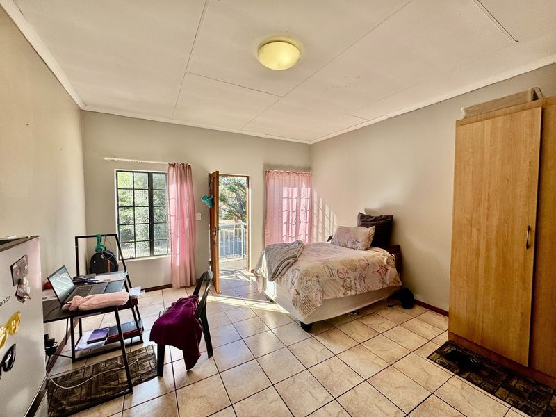 A bedroom featuring tiled flooring, a built-in wardrobe, and direct access to a balcony through a glass door.