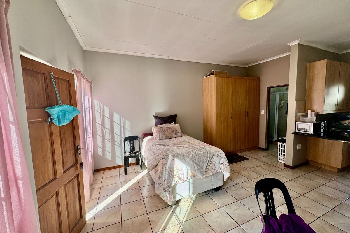 Open-plan studio apartment featuring tiled flooring, a built-in wardrobe, and a compact kitchen area with granite countertops.