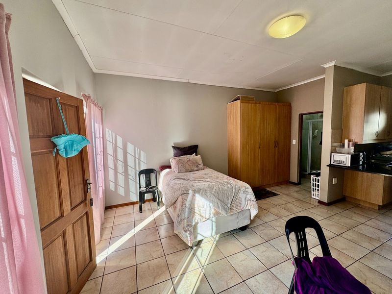 Open-plan studio apartment featuring tiled flooring, a built-in wardrobe, and a compact kitchen area with granite countertops.