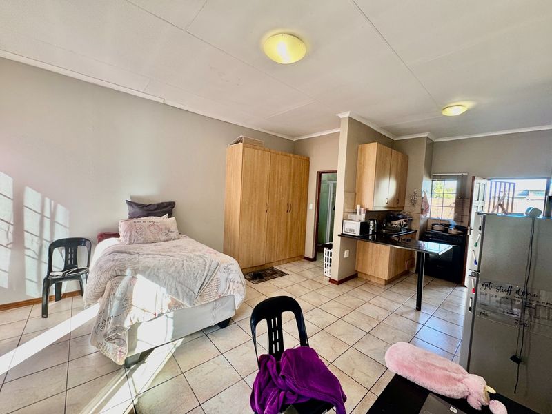 Open-plan studio apartment featuring tiled flooring, built-in bedroom cupboards, and a functional kitchen area with granite countertops and built-in stove.