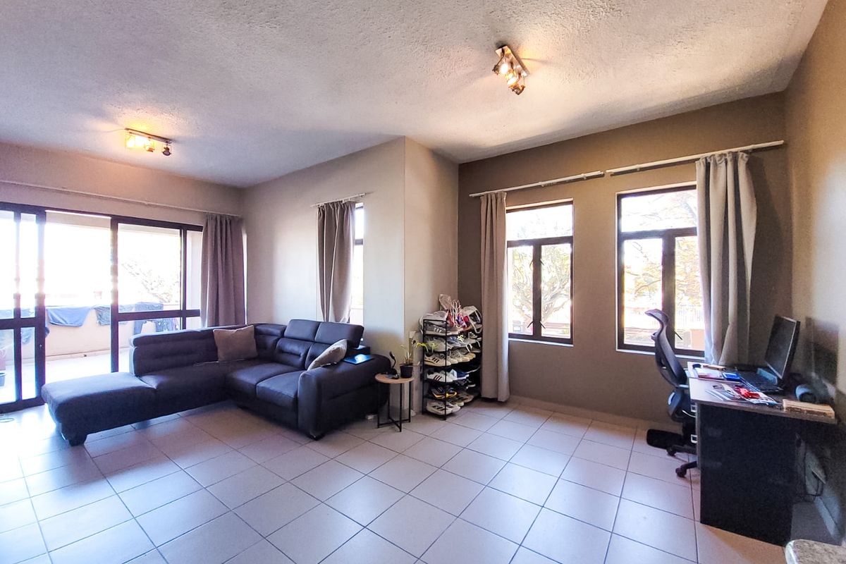 Spacious open-plan living area featuring tiled flooring, large windows for natural light, and direct access to an outdoor balcony through sliding glass doors.