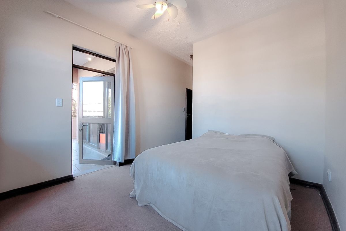 A bedroom featuring carpeted flooring, a ceiling fan, and a glass sliding door providing access to an outdoor area.