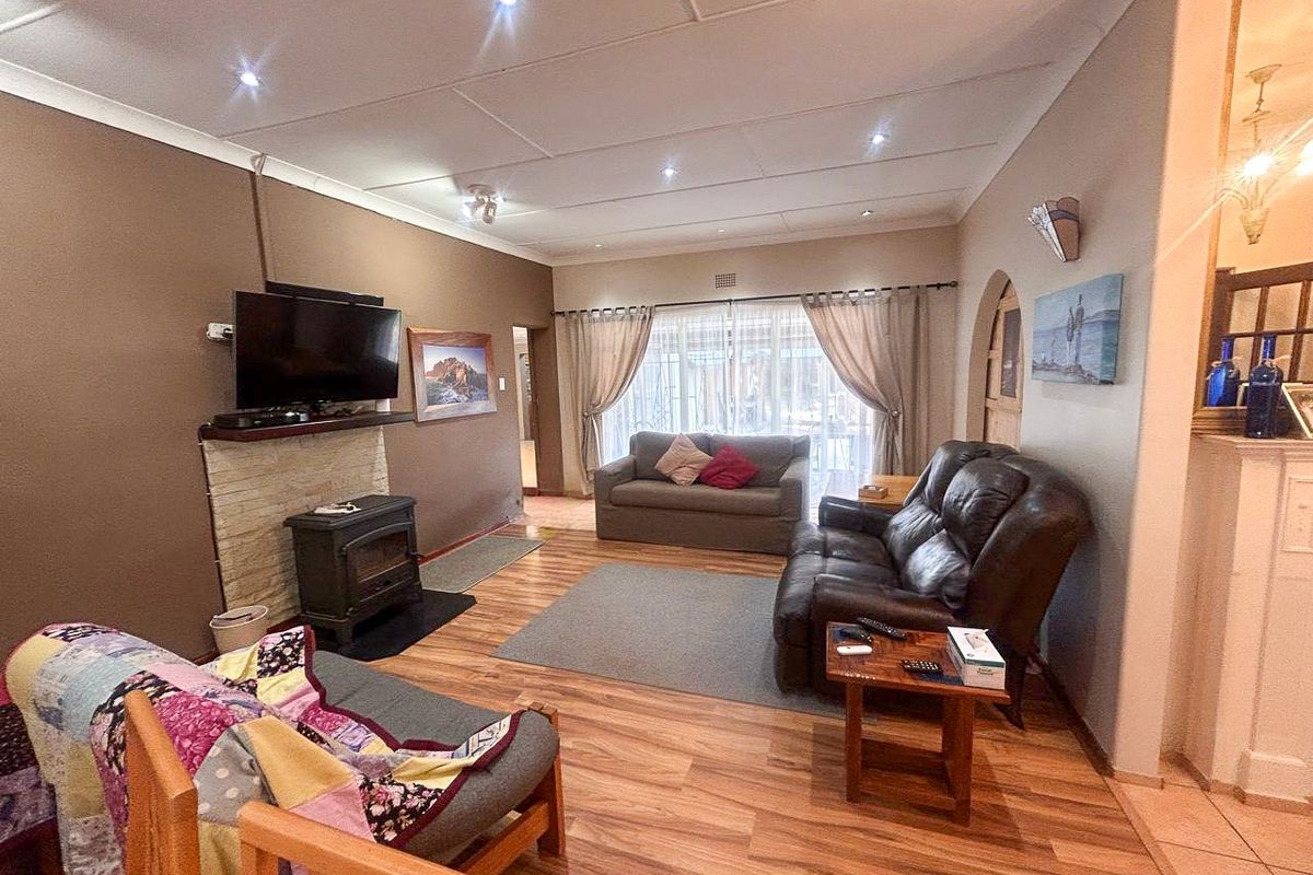 Spacious living room featuring laminate flooring, a stone-surround freestanding fireplace, and recessed lighting, creating a comfortable and functional family area.