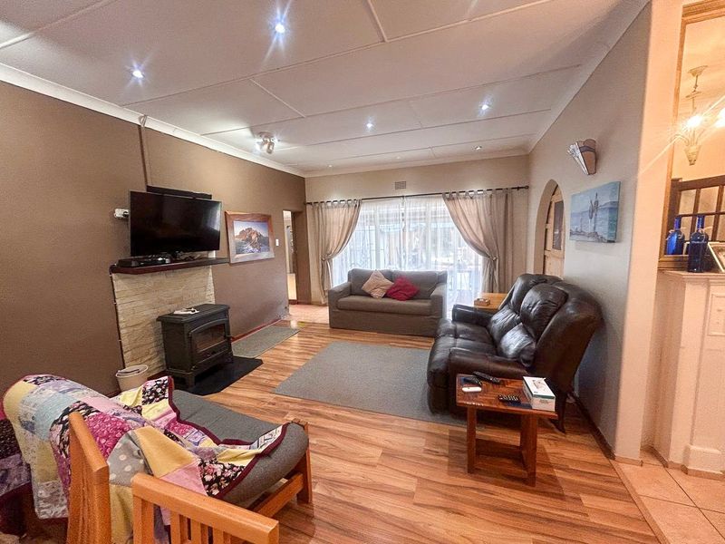 Spacious living room featuring laminate flooring, a stone-surround freestanding fireplace, and recessed lighting, creating a comfortable and functional family area.
