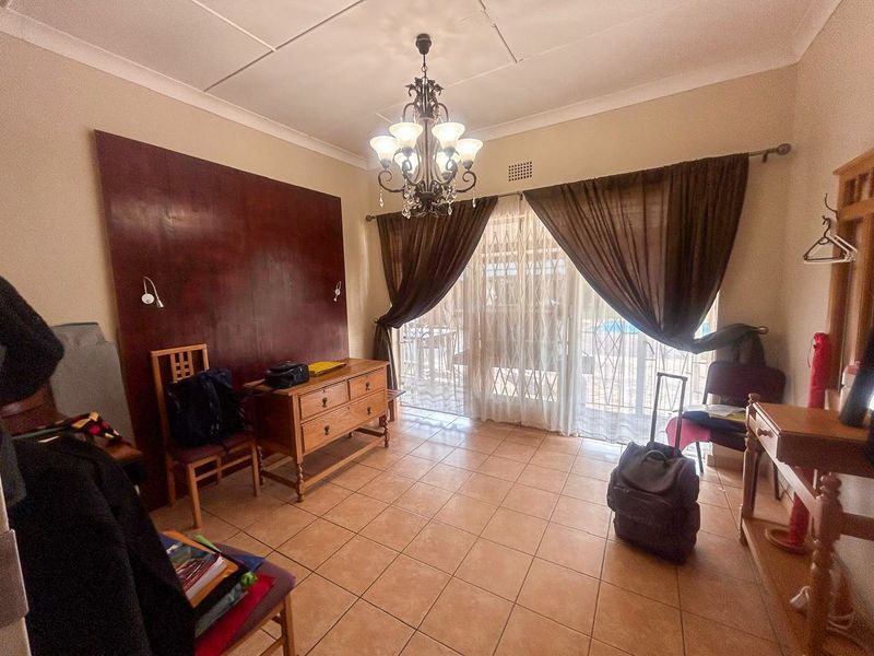 A bedroom featuring tiled flooring, a decorative chandelier, and sliding glass doors leading to an outdoor area.