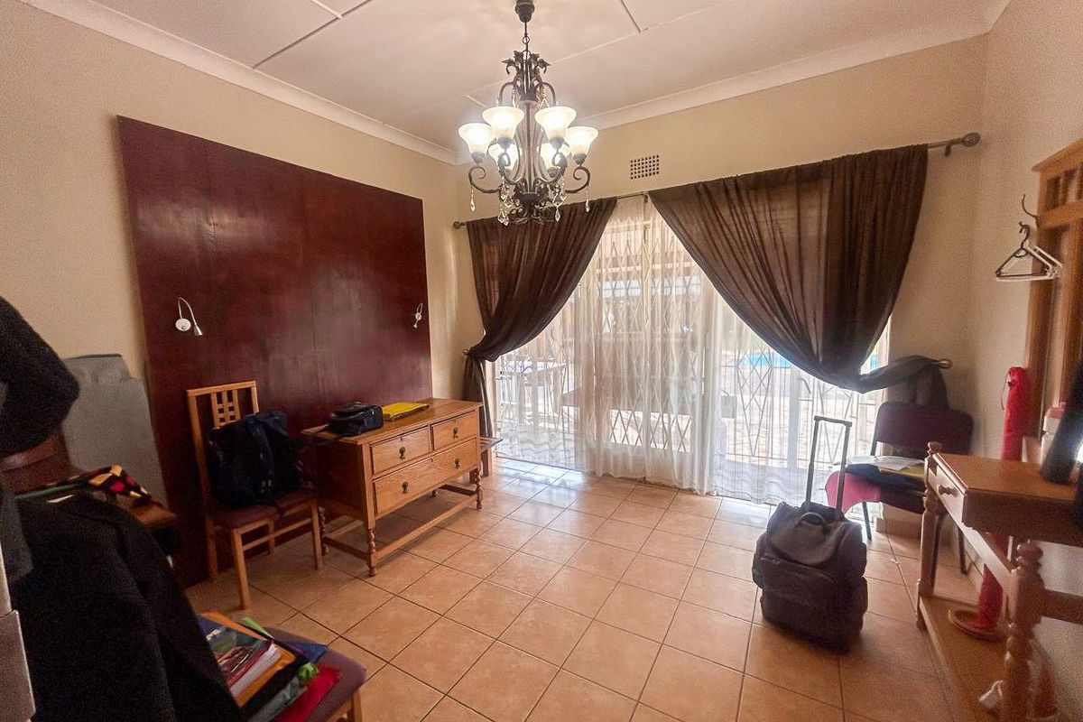 A bedroom featuring tiled flooring, a decorative chandelier, and sliding glass doors leading to an outdoor area.