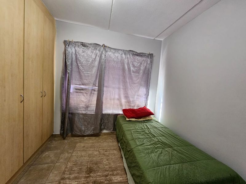 A functional bedroom featuring built-in cupboards and tiled flooring, providing a practical living space.