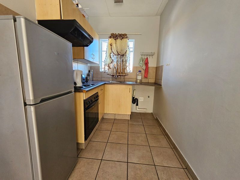 A compact kitchen featuring laminate cabinetry, a built-in oven with extractor fan, tiled flooring, and a tiled backsplash.