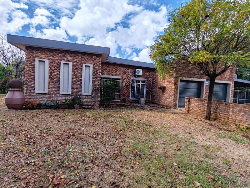 Front elevation of a face brick house featuring a double garage with roller shutter doors and security-fitted windows.
